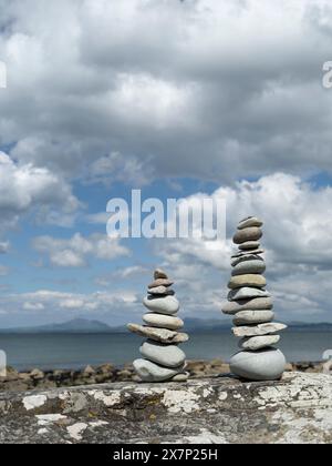 Pierres zen équilibrées sur un grand rocher sur une plage galloise lors d'une belle journée de printemps avec les montagnes de la péninsule de Llyn et la mer en arrière-plan Banque D'Images