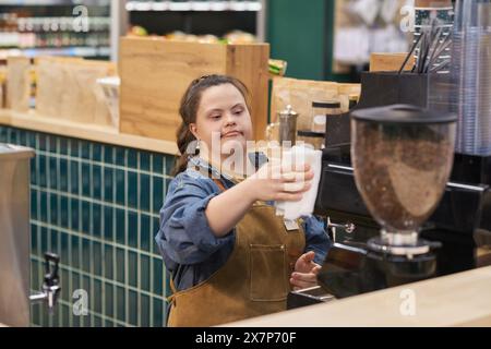 Portrait de taille haute de jeune femme avec le syndrome de Down travaillant comme barista dans la zone de café au supermarché profitant de l'espace de copie de formation professionnelle Banque D'Images