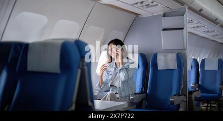 Femme d'affaires voyageant en avion et faisant un appel téléphonique Banque D'Images