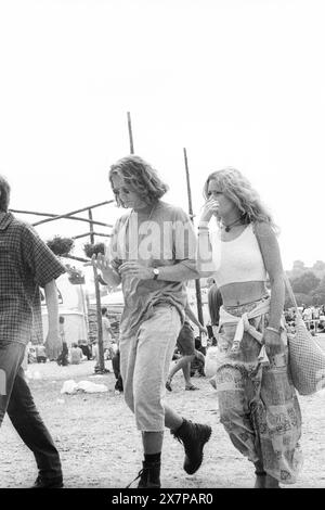 COOL COUPLE, FOULE, HEATWAVE, NME STAGE, GLASTONBURY 95 : un couple cool parmi les festivaliers de la mode des années 90 marchent à travers la zone des stands dans la vague de chaleur extrême de l'été près du second NME Stage Field et la foule au Glastonbury Festival, Pilton Farm, Somerset, Angleterre, 24 juin 1995. En 1995, le festival a célébré son 25e anniversaire. Beaucoup de gens ont lutté avec un coup de chaleur lors du week-end particulièrement chaud. Photo : ROB WATKINS Banque D'Images