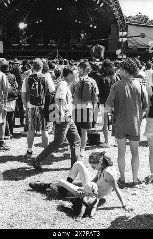 MÈRE ET ENFANT, FOULE, CANICULE, SCÈNE NME, GLASTONBURY 95: une jeune mère et un enfant s'écrasent sur l'herbe et jouent ensemble devant un groupe live dans la canicule estivale extrême au deuxième NME Stage Field et la foule au Glastonbury Festival, Pilton Farm, Somerset, Angleterre, 24 juin 1995. En 1995, le festival a célébré son 25e anniversaire. Beaucoup de gens ont lutté avec un coup de chaleur lors du week-end particulièrement chaud. Photo : ROB WATKINS Banque D'Images