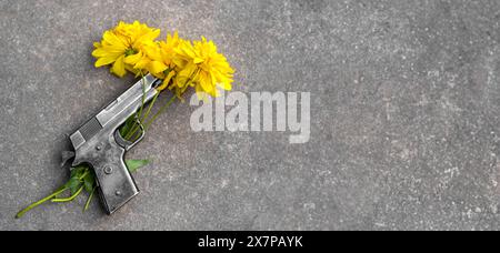 Pistolet et fleurs jaunes sur asphalte. concept de mémoire, fragilité de la paix, pas de guerre, arrêter la guerre, paix mondiale, pacifisme. Bannière, espace copie, espace texte, TEM Banque D'Images