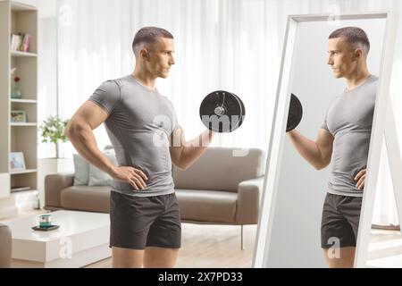Homme exerçant avec un haltère devant un miroir dans un salon Banque D'Images