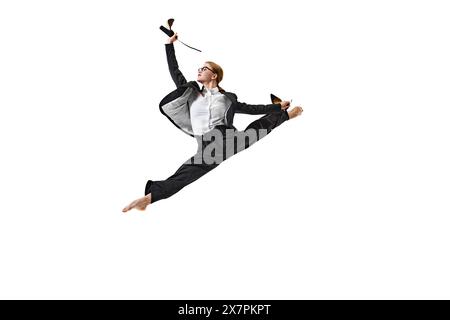 Approche intrépide des défis. Femme en costume d'affaires exécutant un saut parfait, tenant ses chaussures sur fond blanc de studio. Banque D'Images