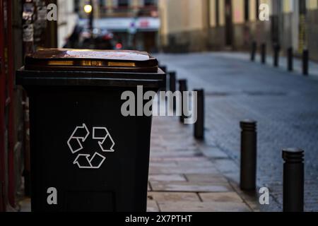 Poubelle noire avec le symbole de recyclage sur le côté de la rue Banque D'Images