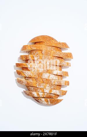 Une image montrant un pain au levain fraîchement cuit coupé en tranches nettes, disposées artistiquement sur un fond blanc. Banque D'Images