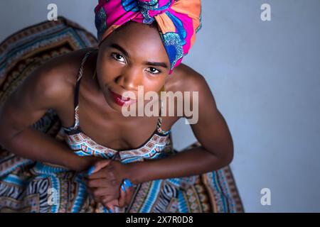 Jeune femme africaine confiante dans un tour de tête vibrant et une tenue traditionnelle. Portrait de studio mettant en valeur la beauté, la culture et l'élégance. Banque D'Images