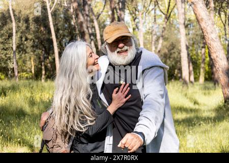 Joyeux couple senior partage un moment tendre sur une promenade ensoleillée à travers un parc luxuriant, illustrant l'amour durable et la compagnie Banque D'Images