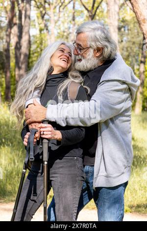 Un couple aîné aimant partage un moment tendre au cours d'une promenade tranquille dans un parc ensoleillé l'homme et la femme, tous deux avec les cheveux gris, sourire affectueusement à chaque ot Banque D'Images