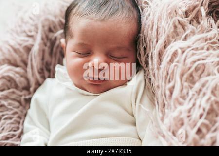 Une image sereine capturant un nouveau-né endormi, enveloppé confortablement dans une couverture douce et texturée, reflétant l'innocence et la tranquillité du sommeil Banque D'Images