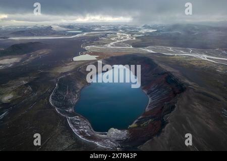 Une capture aérienne époustouflante met en valeur un lac tranquille niché dans le paysage spectaculaire et accidenté des terrains montagneux, sous un ciel sombre Banque D'Images