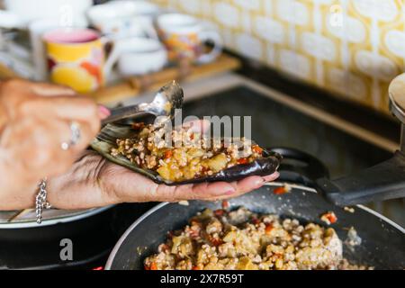 Un gros plan capturant les mains d'une femme âgée alors qu'elle prépare habilement des plats chez elle, mettant l'accent sur la cuisine familiale Banque D'Images