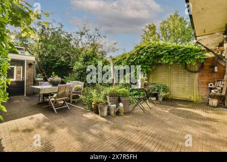 Un jardin pittoresque avec une salle à manger, une végétation luxuriante et des accents en bois au Meester Rendorplaan 8, parfait pour la détente en plein air ou le divertissement Banque D'Images