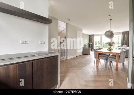 Intérieur élégant d'une maison présentant une cuisine moderne avec un comptoir en bois sombre et salle à manger la pièce est baignée de lumière naturelle, avec une peluche Banque D'Images