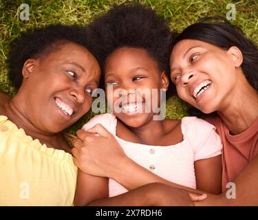 Vue sur la famille féminine de trois générations rire et s'allonger sur l'herbe en plein air dans la campagne Banque D'Images