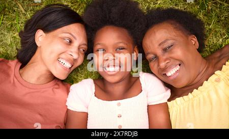 Vue sur la famille féminine de trois générations rire et s'allonger sur l'herbe en plein air dans la campagne Banque D'Images