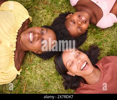 Regardant vers le bas sur la famille féminine de trois générations avec les yeux fermés rire et allonger sur herbe à l'extérieur Banque D'Images