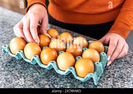 mains de femme prenant un œuf dans un seau sur le comptoir de la cuisine Banque D'Images
