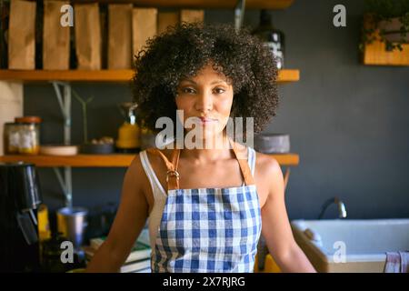 Portrait de femme par étagères travaillant dans Sustainable Plastic Free Grocery Store portant tablier Banque D'Images