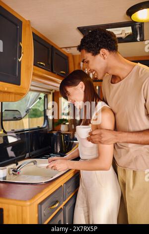 Un homme et une femme, de races différentes, debout ensemble dans une cuisine à côté d'un évier. Banque D'Images