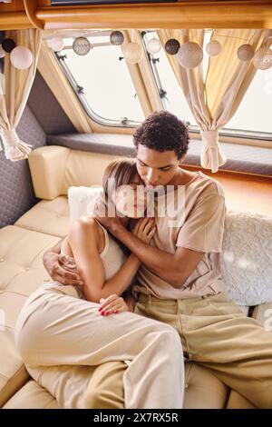 Un couple interracial se détend sur un canapé dans un van, profitant d'un moment de paix ensemble Banque D'Images