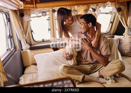 Un couple interracial se détend sur un canapé dans un van élégant, profitant d'une escapade romantique Banque D'Images