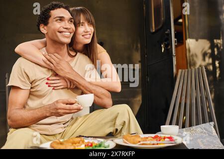 Un homme et une femme, un couple interracial, assis sur un banc, jouissant mutuellement de compagnie dans un cadre paisible. Banque D'Images