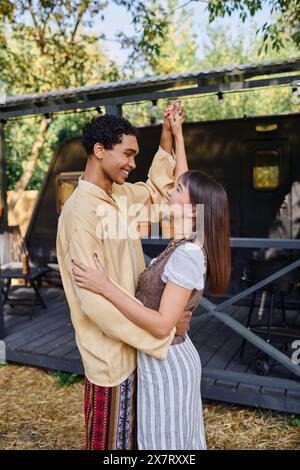 Un homme et une femme dansent gracieusement devant une tente colorée sous le ciel, entourés par la nature. Banque D'Images