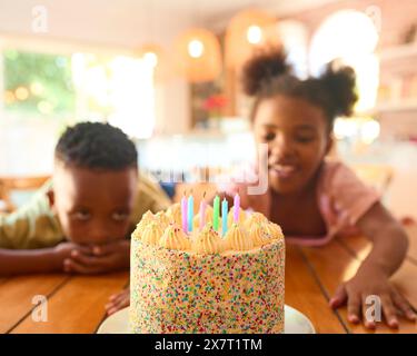 Deux enfants regardant Hungrily à Tasty Birthday Cake on table for Party Banque D'Images