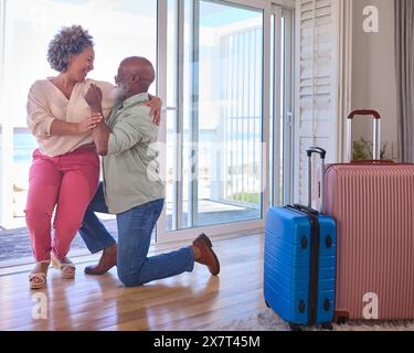 Couple d'âge mûr avec homme proposant le mariage agenouillé et donnant anneau de femme dans la propriété de front de mer Banque D'Images