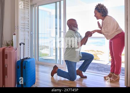 Couple d'âge mûr avec homme proposant le mariage agenouillé et donnant anneau de femme dans la propriété de front de mer Banque D'Images