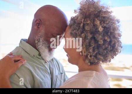 Gros plan de couple d'âge mûr amoureux embrassant dans Beachfront House surplombant l'océan pour des vacances d'été Banque D'Images