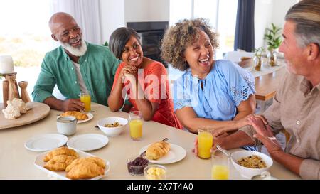Groupe d'amis adultes souriants en vacances ou à la maison mangeant le petit déjeuner ensemble Banque D'Images