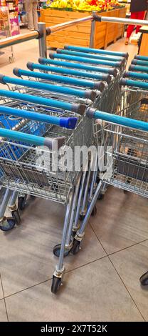 Une rangée de chariots vides alignés soigneusement dans une allée d'épicerie, prêts à être utilisés par les clients. Banque D'Images