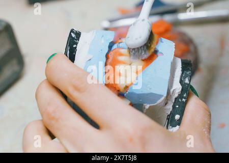 Un technicien dentaire fabrique habilement des prothèses dentaires à l'aide d'outils spécialisés dans un gros plan détaillé, mettant en valeur l'artisanat et la précision. Banque D'Images