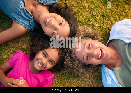 Vue sur la famille féminine de trois générations rire et s'allonger sur l'herbe en plein air dans la campagne Banque D'Images