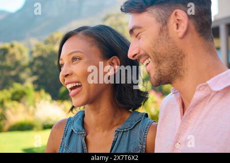 Portrait de rire et sourire couple multi-racial debout à l'extérieur dans la campagne Banque D'Images