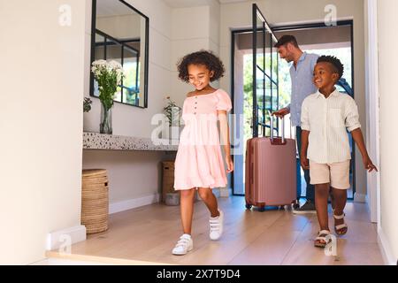 Famille multiraciale avec père et enfants arrivant dans la maison ou l'appartement pour les vacances d'été Banque D'Images