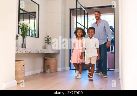 Famille multiraciale avec père et enfants arrivant dans la maison ou l'appartement pour les vacances d'été Banque D'Images