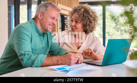 Couple mature multi-racial à la maison avec ordinateur portable examinant les finances domestiques Banque D'Images