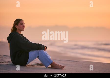 Décontractée jeune femme regardant beau lever de soleil matin sur la plage et la mer en Afrique du Sud Banque D'Images