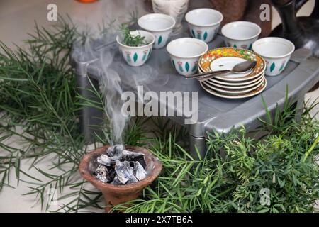 Des grains de café fraîchement torréfiés, un mortier et un pilon avec du jebena et de la fumée d'encens créent une configuration traditionnelle de cérémonie du café éthiopien Banque D'Images