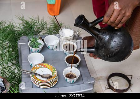 Des grains de café fraîchement torréfiés, un mortier et un pilon avec du jebena et de la fumée d'encens créent une configuration traditionnelle de cérémonie du café éthiopien Banque D'Images