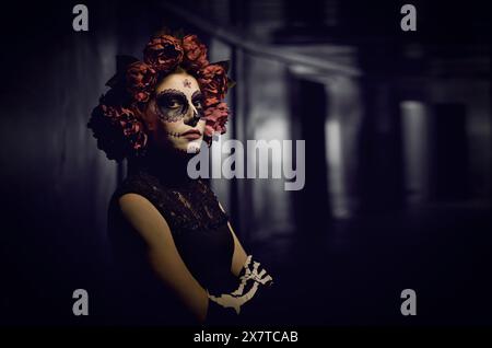 Portrait de femme habillée pour Halloween ou jour des morts debout sur fond sombre Banque D'Images