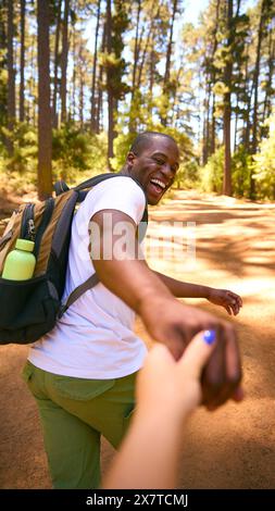 POV photo d'un couple amoureux portant des sacs à dos se tenant la main faisant une randonnée le long de Trail à travers la campagne Banque D'Images