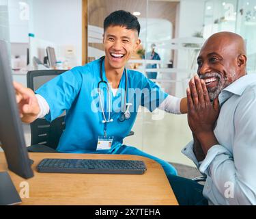 Médecin masculin portant des gommages au rendez-vous de l'hôpital donnant de bonnes nouvelles au patient masculin mature Banque D'Images