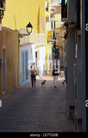 Villajoyosa, Espagne - 15 mai 2024 : les gens marchent le long des rues confortables de Villajoyosa avec des maisons colorées le jour ensoleillé. La Vila Joiosa - ville côtière, Val Banque D'Images