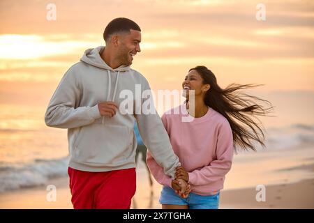 Gros plan de couple dans Casual Clothing on Vacation tenant la main courant le long de Beach Shore à Dawn Banque D'Images
