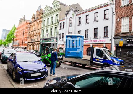 Belfast, County Antrim, Northern Ireland May 06 2024 - hommes chargeant des toilettes portatives sur un camion à plateau dans une rue animée de Belfast Banque D'Images