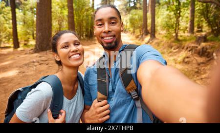 Plan POV de couple marchant le long de Trail à travers la campagne posant pour Selfie sur téléphone portable Banque D'Images